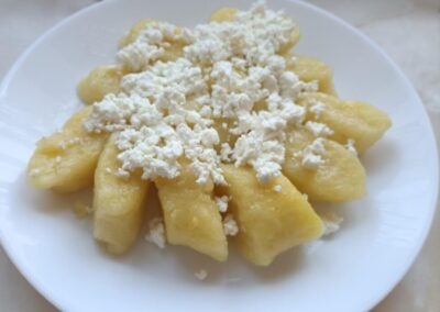 Porcja kopytek z białym serem na białym talerzu.